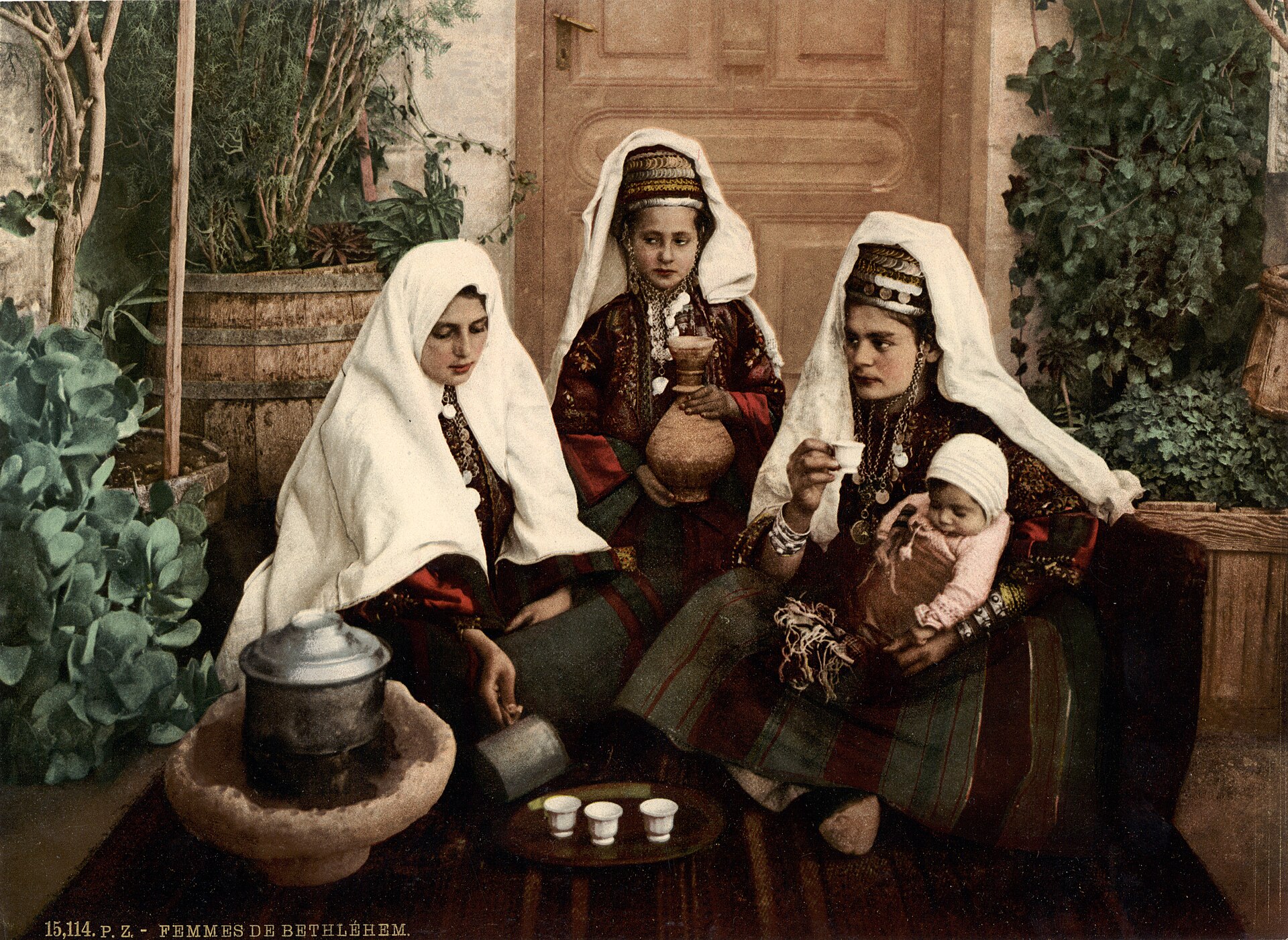 A group of Bethlehem women in traditional embroidered dress and headdresses, hand-colored photograph from about 1895